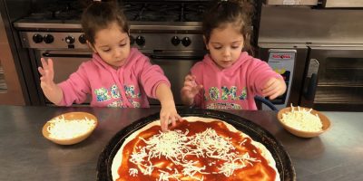 Two pre-schoolers making pizza