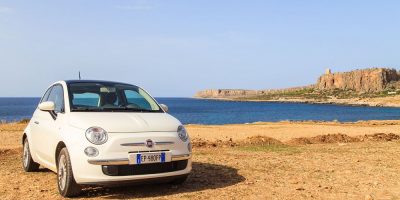 Little white Fiat car parked on Italian beach