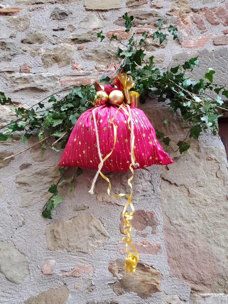 Filled red bag with gold ribbon hanging on wall for decoration.