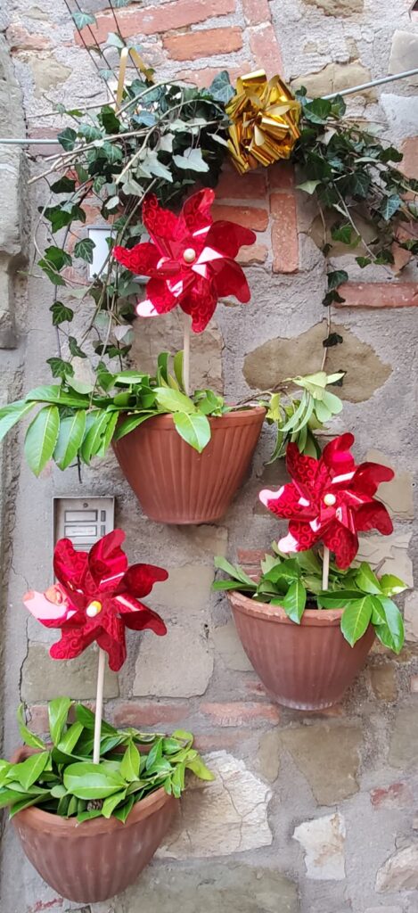 Red pinwheels with greenery in pots as decorations.