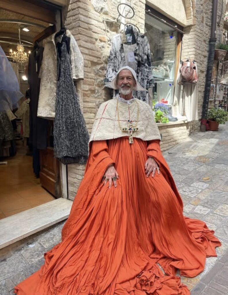 Italian man in flowing orange robes draping the ground