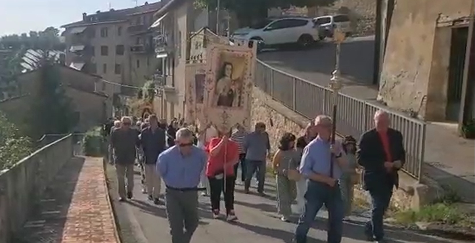 Group of Italian villagers in procession with saint banners.