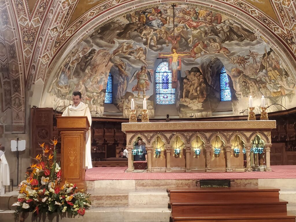 Deacon Dom Pastore reading the Gospel in the Lower Crypt of the Basilica of St. Francis in Assisi, Italy